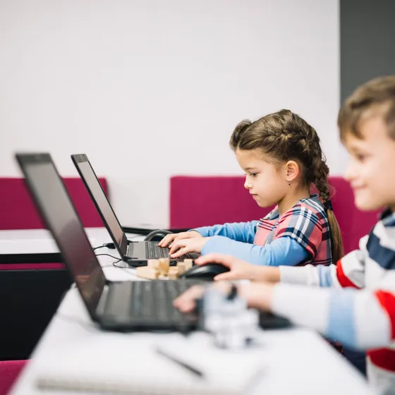 Two children using a laptop in a classroom